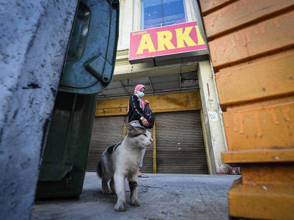 Seorang wanita melalui sebuah kedai ketika tinjauan Perintah Kawalan Pergerakan (PKP) di sekitar Jalan Chow Kit hari ini. - Foto Bernama