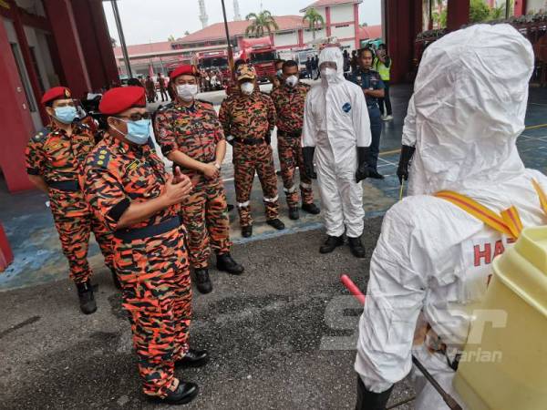 Hamdan(kiri) memberi taklimat kepada anggota bomba dari Pasukan Khas Bahan Kimia Berbahaya (HAZMAT) yang bertanggungjawab membuat proses sanitasi. 