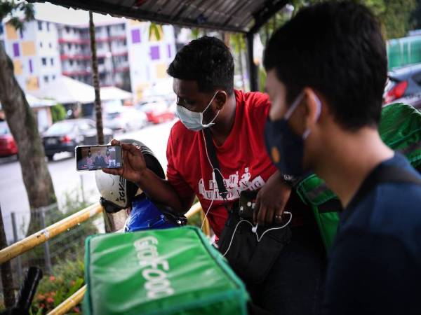 Penunggang Perkhidmatan Penghantaran Makanan, Gan (kanan) bersama rakan sekerjanya. -Foto Bernama