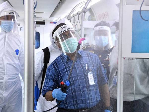 Ismail (depan) melakukan operasi nyah cemar di dalam tren komuter bagi mengekang penularan Covid-19 hari ini. - Foto Bernama