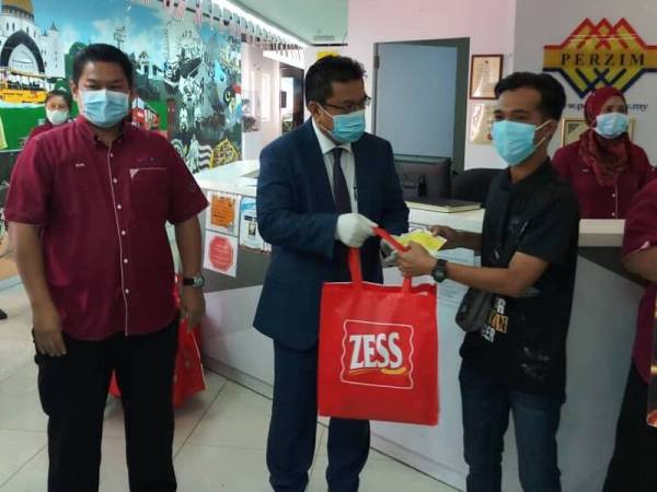 Sulaiman (dua dari kanan) menyampaikan cek dan bantuan kepada seorang penarik beca sambil diperhatikan Pengurus Besar Bahagian Promosi Pelancongan Melaka, Zairi Suboh.