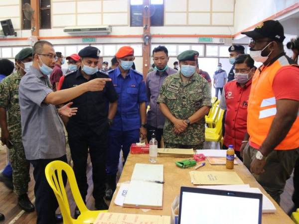 Ayob Khan (dua dari kiri) diberikan taklimat dan penerangan ringkas melawat pusat bekalan makanan Jabatan Kebajikan Masyarakat dalam Op Covid-19 di bandar Simpang Renggam, Kluang, Johor di sini hari ini.