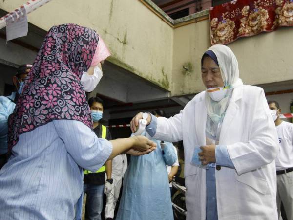 Zuraida (kanan) membantu meletakkan cecair pembasmi kuman pada tangan seorang penduduk, Emanita Masnur (kiri) sebelum meninjau Operasi Sanitasi Covid-19 di PPR Taman Putra Damai, Lembah Subang 1 hari ini. - Foto Bernama