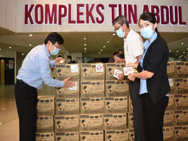 Kon Yeow (kiri) menerima menerima sumbangan sarung tangan getah daripada syarikat pengeluar sarung tangan getah utama dunia, Top Glove Corporation Berhad (Top Glove).