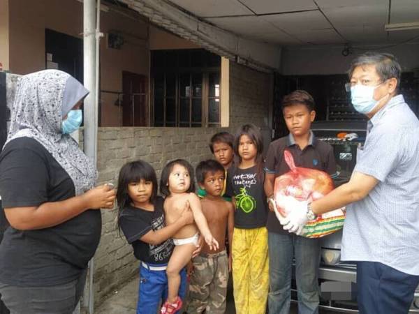 Kok Yew menyerahkan bantuan keperluan asas kepada anak Solehah, Syazwan Mt Suri, 17, ketika ditemui di rumah mereka di Taman Nuri di sini hari ini.