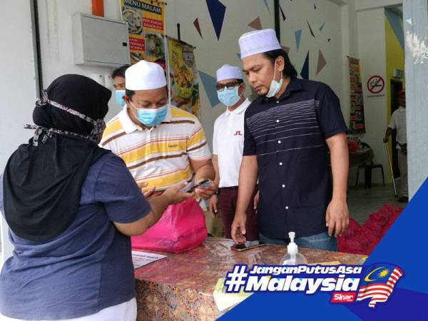 Mohd Asna membantu mengagihkan bantuan kepada pemohon yang hadir hari ini.