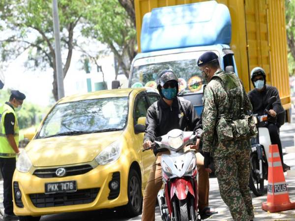 Anggota tentera membantu anggota polis pada sekatan jalan raya sepanjang Perintah Kawalan Pergerakan (PKP) fasa kedua. - Foto Bernama