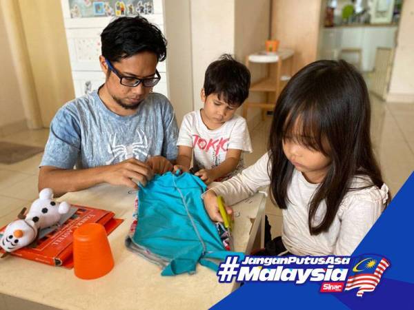 Muhammad Faisal (kiri) mengajar anak-anaknya membuat beg kitar semula daripada baju terpakai.