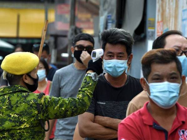 Anggota Rela memeriksa suhu badan orang ramai sebelum memasuki Pasar Taman Lip Sin, Sungai Dua sebagai salah satu langkah untuk mencegah penularan Covid-19. - Foto Bernama