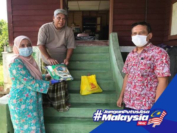 Juwairiya (kiri) bersama petugas menyampaikan bantuan kepada salah seorang penerima di DUN Bukit Melawati.