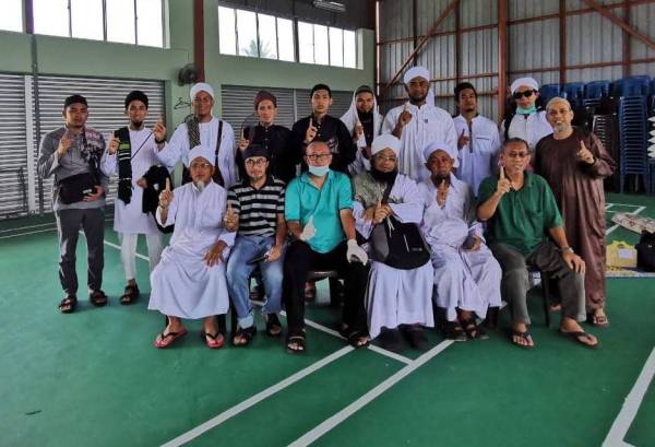 Mohd Abdul Salam (duduk, tiga dari kanan) bersama 13 jemaah tabligh Kuantan tiba dari Miri, Sarawak hari ini. 