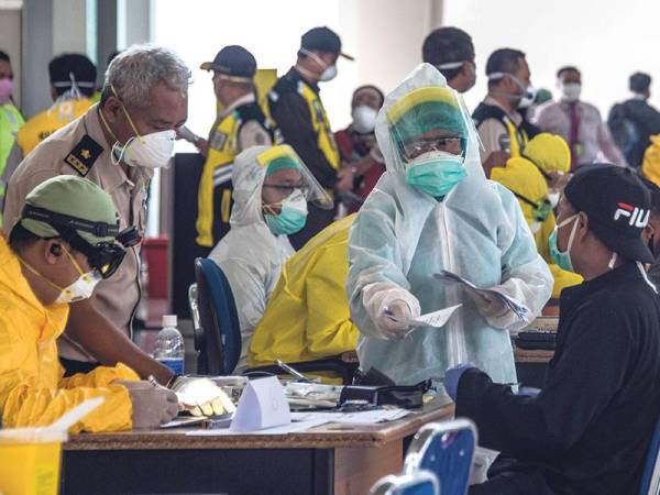 Pegawai perubatan Indonesia melakukan pemeriksaan kesihatan terhadap pekerja asing yang tiba di Lapangan Terbang Surabaya di Jawa Timur. 