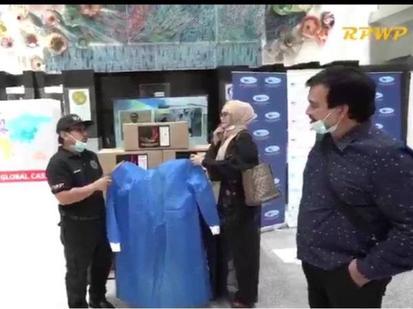 Saiful menunjukkan PPE yang dijahit anak yatim dan asnaf RPWP kepada Siti Nurhaliza pada penyerahan sumbangan itu di IJN semalam.