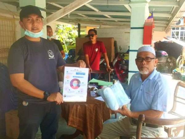 Mohd Imran (kanan) mengedarkan bantuan kecemasan Covid-19 kepada salah seorang penerima di DUN Sungai Panjang di sini hari ini.