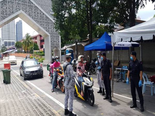 Anggota polis dan tentera yang sedang mengawal pintu keluar dan masuk di Kampong Bharu di sini hari ini.