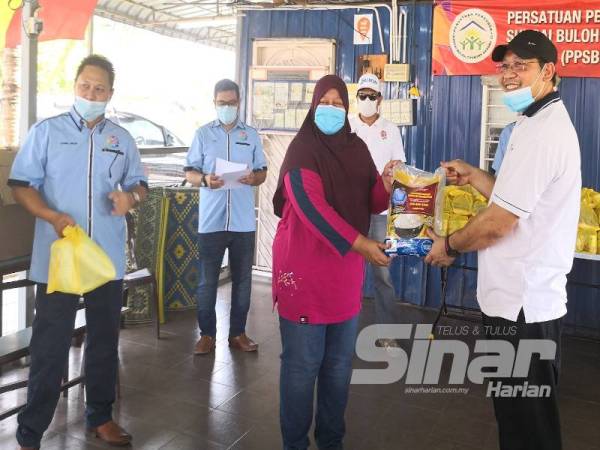 Mohd Khairuddin (kanan) menyampaikan peruntukan kepada salah seorang wakil penerima pada Majlis Penyampaian Sumbangan Barangan Keperluan di Pusat Komuniti Sungai Buloh Country Resort Fasa 3C di sini hari ini.