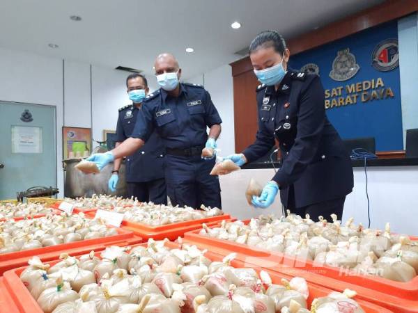 Anbalagan (tengah) bersama pegawainya menunjukkan 1,800 bungkusan air ketum yang dirampas. 