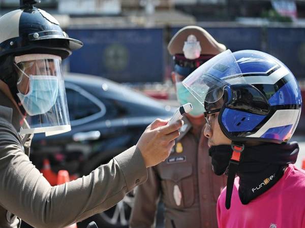 Polis Thailand menjalankan pemeriksaan suhu ke atas pengguna jalan raya di pinggir Bangkok.
