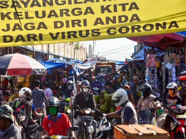 Rakyat Indonesia tidak mempedulikan penjarakan sosial ketika singgah di sebuah pasar pagi di Bekasi, Jawa Barat semalam.