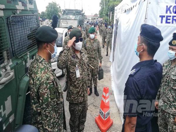 Ahmad Hasbullah (dua dari kiri) ketika tiba di sekatan jalan raya Kampung Gong Pauh di sini hari ini. 