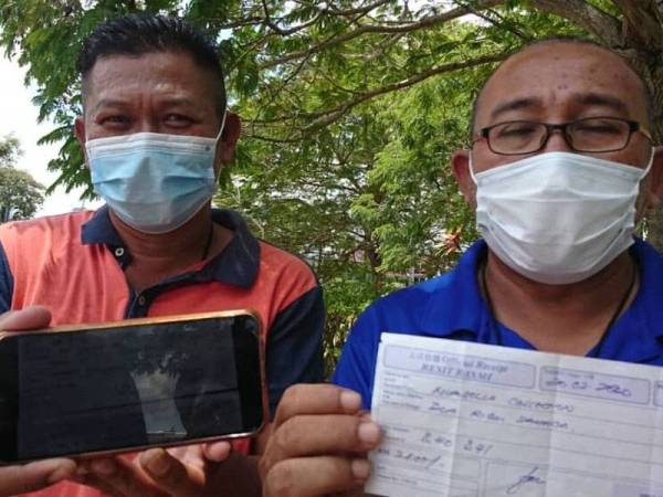 Ramdan (kanan) bersama rakannya menunjukkan resit deposit bayaran khemah Bazar Ramadan MITC.