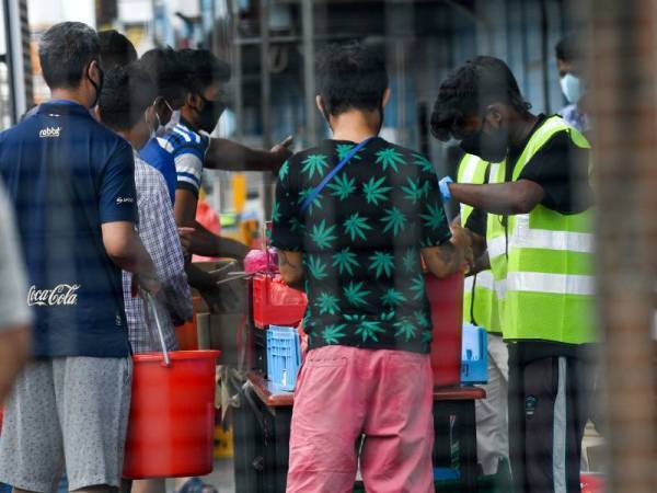 Pekerja asing beratur untuk mendapatkan makanan selepas asrama Tuas Selatan diletakkan di bawah sekatan pemerintah.