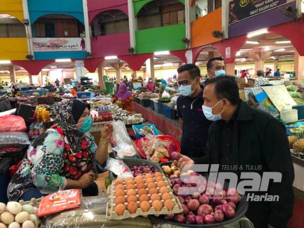 Adnan (kanan) menyantuni peniaga ketika menjalankan pemeriksaan dan pemantauan bekalan serta harga barangan keperluan asas di Pasar Siti Khadijah di sini hari ini.