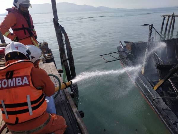 Anggota bomba menjalankan operasi pemadaman kebakaran bot nelayan di perairan Pulau Pangkor. Foto: JBPM Perak. 