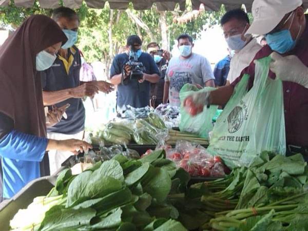 Noor Azman (kanan) dan Norhizam melayan orang ramai yang mahu membeli barangan basah di Pasar Seringgit Ramadan di RUTC Klebang Besar di sini hari ini.