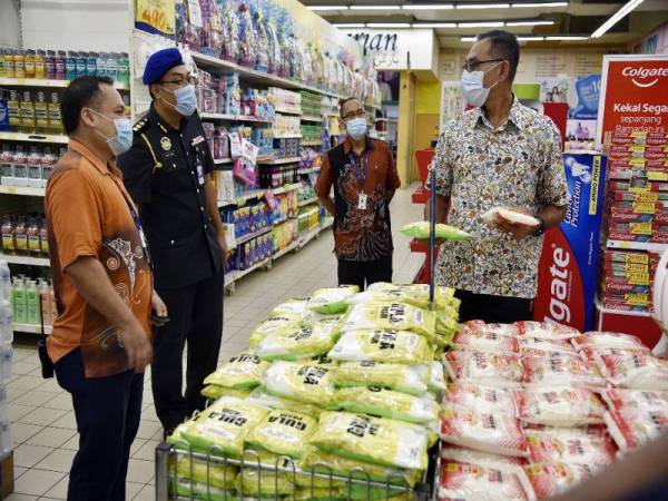 Rosol (kanan) melihat stok gula ketika melakukan tinjauan bekalan makanan dan keperluan sempena Ramadan di sebuah pasar raya hari ini.