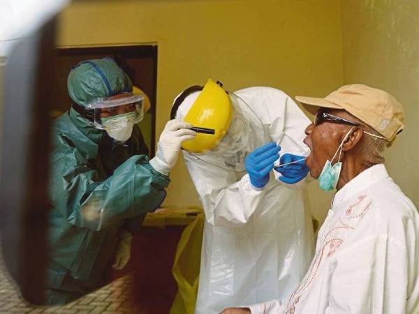 Pasukan perubatan Indonesia menjalankan proses saringan swab Covid-19 ke atas seorang lelaki. - Foto AFP