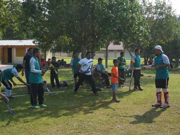 Mohamad (kanan) membantu melatih sebahagian pemain hoki daerah Kerian bagi menghadapi kejohanan peringkat daerah dan negeri.