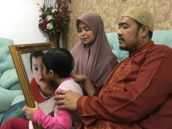 Nurul Hasya mencium potret Allahyarham Nurul Hayfa Farha sambil diperhatikan Mohd Fakhrulrazi dan Hazirah.