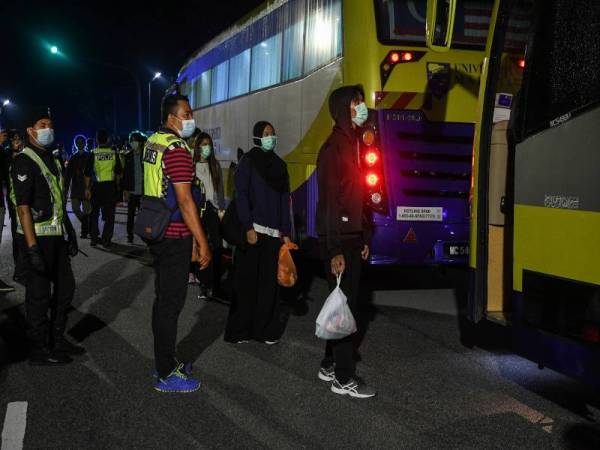 Kelihatan pelajar mengamalkan penjarakan sosial satu meter semasa beratur untuk menaiki bas ketika Proses Penghantaran Pulang Pelajar IPT ke Kampung Halaman di Dewan Tuanku Canselor Universiti Malaya hari ini. - Foto Bernama