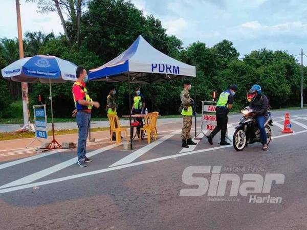 Anuar Bakri (kiri) memantau sekatan jalan raya yang diadakan di Jalan Pedas- Tampin semalam.