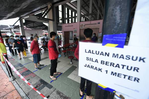 Peniaga dan pekerja pasar beratur mengikut jarak yang ditetapkan pada saringan ke atas peniaga dan pekerja Pasar Taman Megah. -Foto Bernama