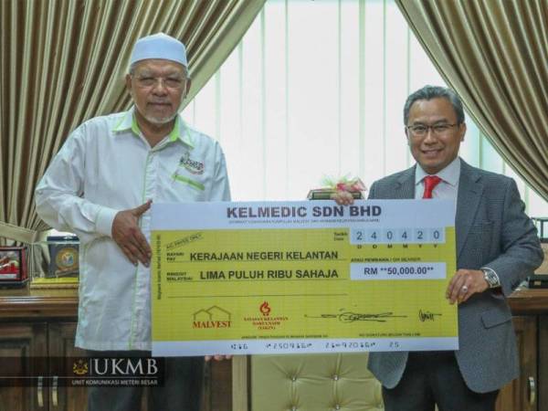 Ahmad (kiri) menerima replika cek berjumlah RM50,000 daripada Kelmedic Sdn Bhd.