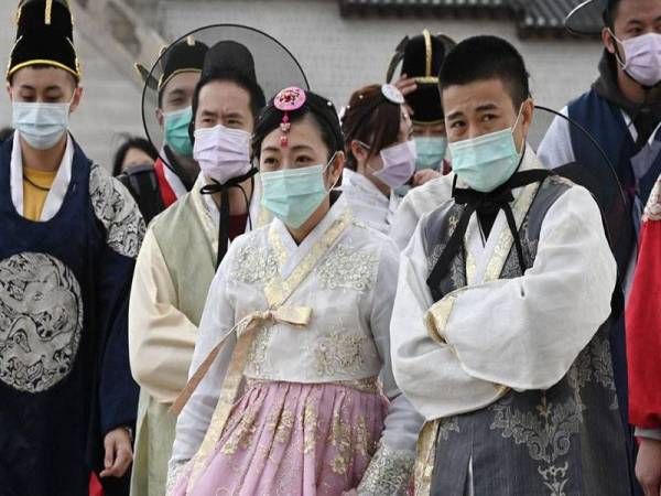 Pelancong di Korea Selatan memakai topeng muka. - Foto AFP