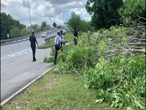 Anggota trafik dari pasukan polis rondaan khas Perintah Kawalan Pergerakan (PKP) Ibu Pejabat Polis Daerah Seremban sedang menebas ranting pokok yang menghalang laluan berkenaan.