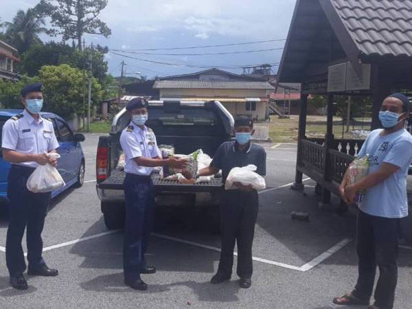 Timbalan Pengarah Operasi Komander Maritim Ariffin Ghazali (dua kanan) menyampaikan sumbangan kepada wakil Persatuan Nelayan Kuala Terengganu Selatan untuk diagihkan kepada keluarga komuniti nelayan yang terjejas sepanjang tempoh PKP