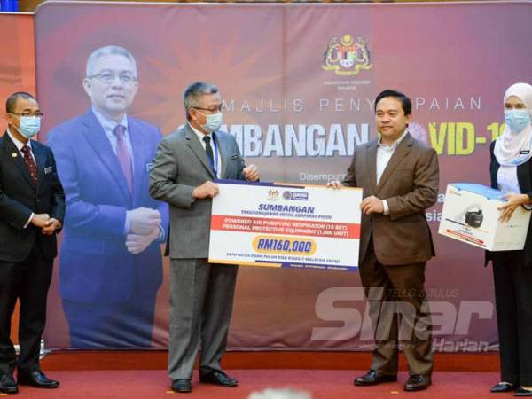 Wan Saiful (dua dari kanan) menyerahkan sumbangan PPE dan PAPR daripada PTPTN kepada Adham di Putrajaya semalam. - Foto Sinar Harian/SHARIFUDIN ABDUL RAHIM