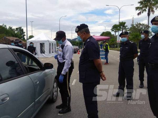 Abd Tahim (dua dari kiri) turut meluangkan masa berada di sekatan jalan raya di Tanjung Lumpur di sini bagi melawat anggota PDRM menjalankan Ops Covid-19.