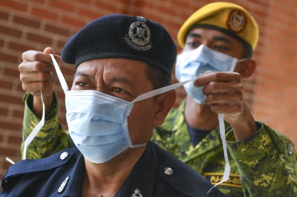 Orang awam kini digalakkan memakai topeng muka ketika berurusan walaupun tidak bergejala. -Foto Bernama