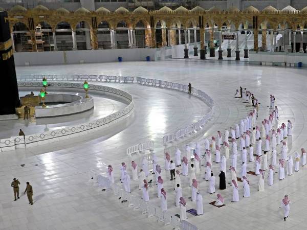 Umat Islam menunaikan solat Isyak di Masjidil Haram selepas pihak berkuasa membenarkan kemasukan terhad di situ. - AFP