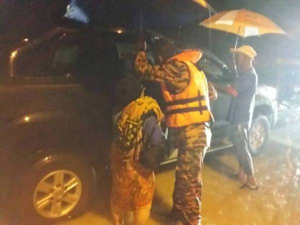 Anggota bomba membantu memindahkan mangsa banjir di Kampung Dato Johan, Jempol semalam.