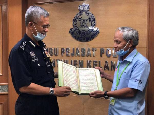 Hasanuddin (kiri) melihat al-Quran yang diwakafkan oleh orang ramai melalui WUIF dan KMK yang disampaikan oleh Muhammad Nasir.