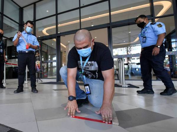 Pengurus Operasi dan Pengurusan Korporat KTCC Mall, Tengku Nurosmar Shah Tengku Abdullah (dua dari kiri) melekatkan pita pelekat bagi tujuan penjarakan satu meter ketika tinjauan di KTCC Mall semalam.