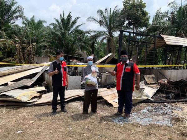 Ketua Biro Kebajikan UMNO Bahagian Batu Pahat, Mohd Hamidi Mad Tap (kanan) menyerahkan bantuan kepada Mustaffa Nawi (tengah) selepas rumahnya musnah dalam kebakaran di Kampung Baru, Senggarang, Batu Pahat, Johor awal pagi.