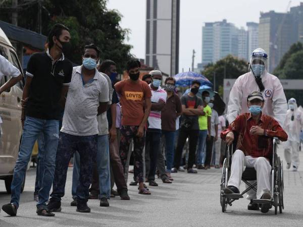  Petugas Kementerian Kesihatan Malaysia membantu seorang warga emas menggunakan kerusi roda sebelum melakukan pemeriksaan saringan koronavirus (Covid-19) di Pasar Chow Kit hari ini. - Foto Bernama