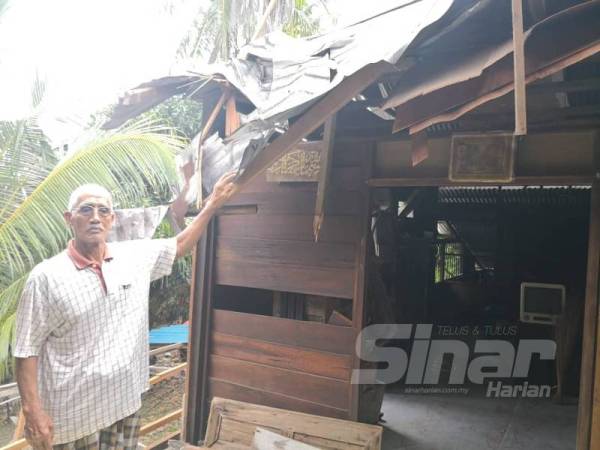 Mohd Bakri menunjukkan bumbung rumahnya ranap ditimpa pokok kelapa dalam kejadian di Kampung Teluk Rhu di sini pagi semalam